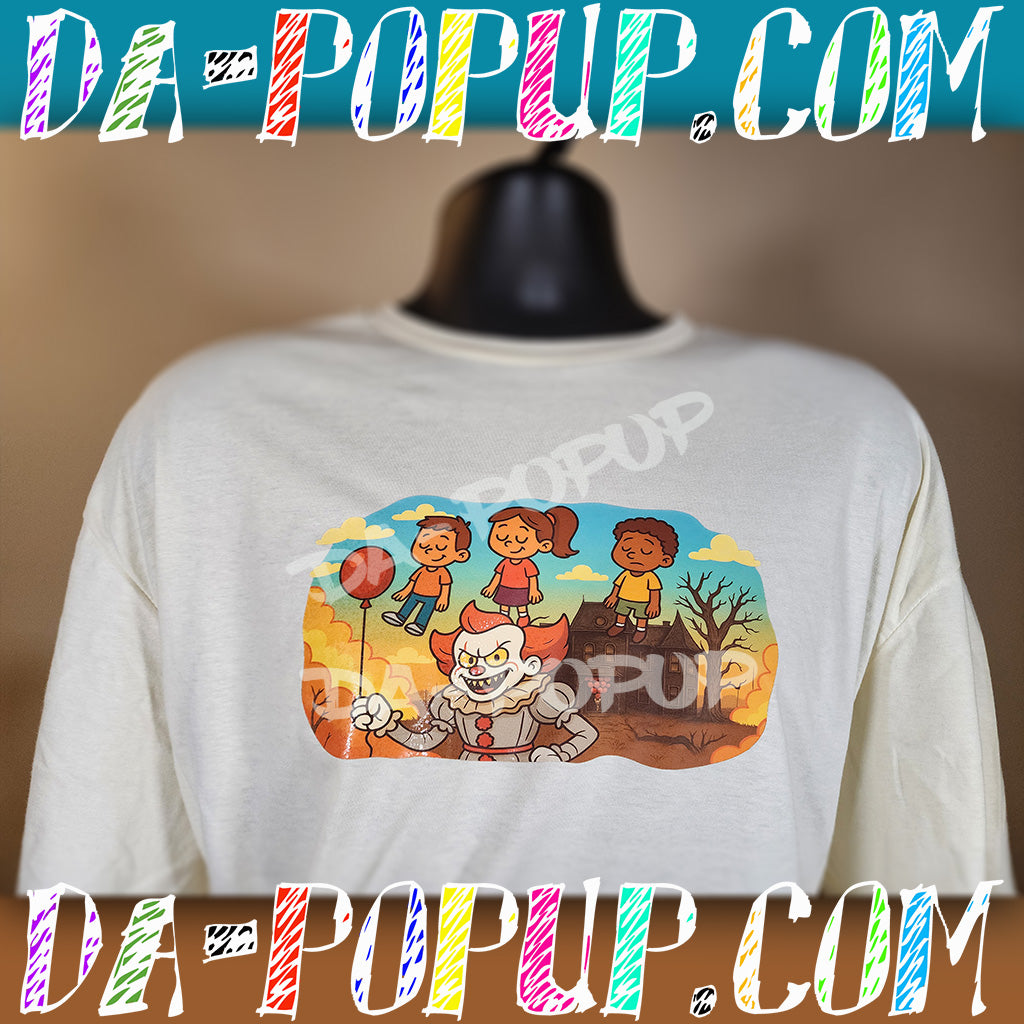 White t-shirt featuring a cartoon Pennywise clown holding red balloons with kids floating above a haunted house background